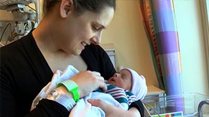 A woman wearing two hospital ID bracelets cradles her baby