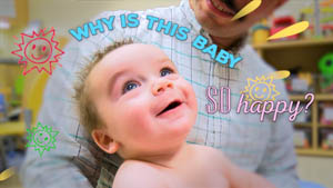 A smiling baby held by his parent looks up. Text reads "Why is this baby so happy?"