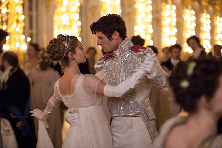 Ballroom dance scene of Lily James as Natasha on the left and James Norton as Andrei on the right.