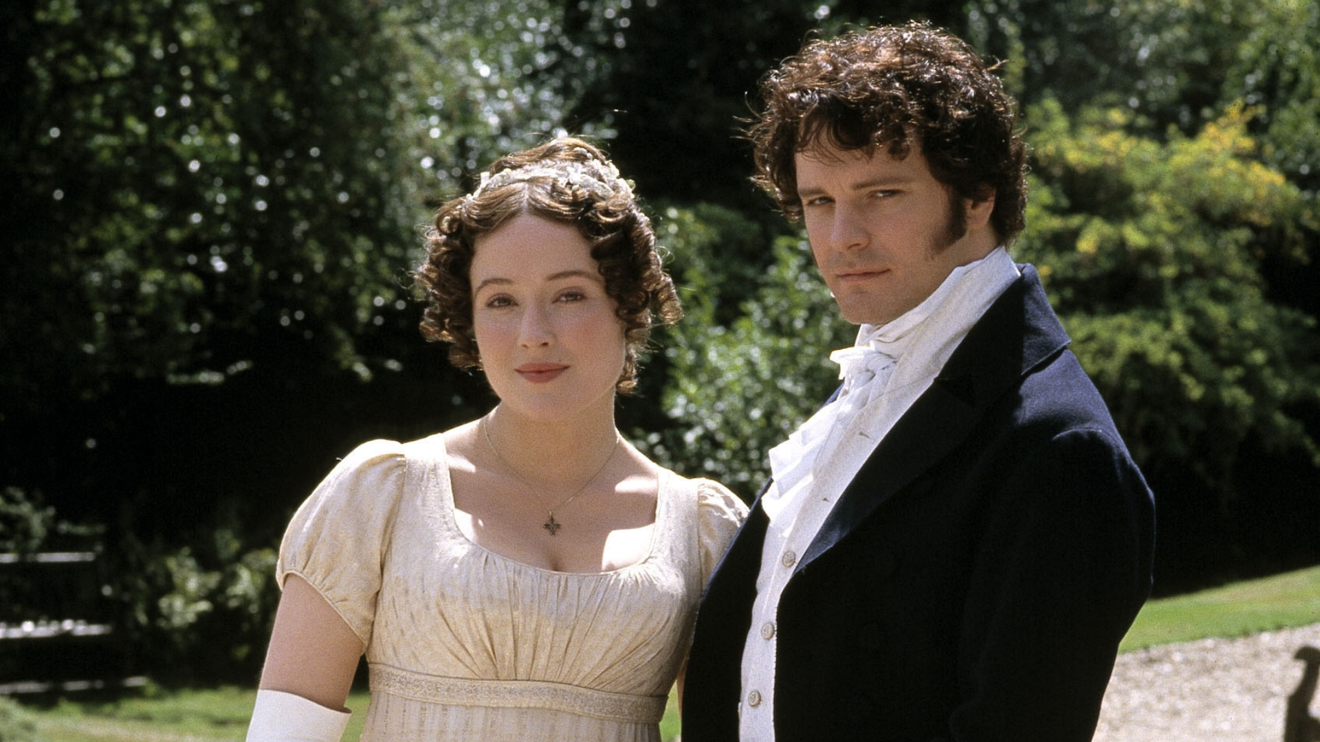 From left, Elizabeth Bennet and Mr. Darcy. Elizabeth has a happy expression and is wearing a high-waisted gown, and Mr. Darcy has a serious expression and is wearing a suit.