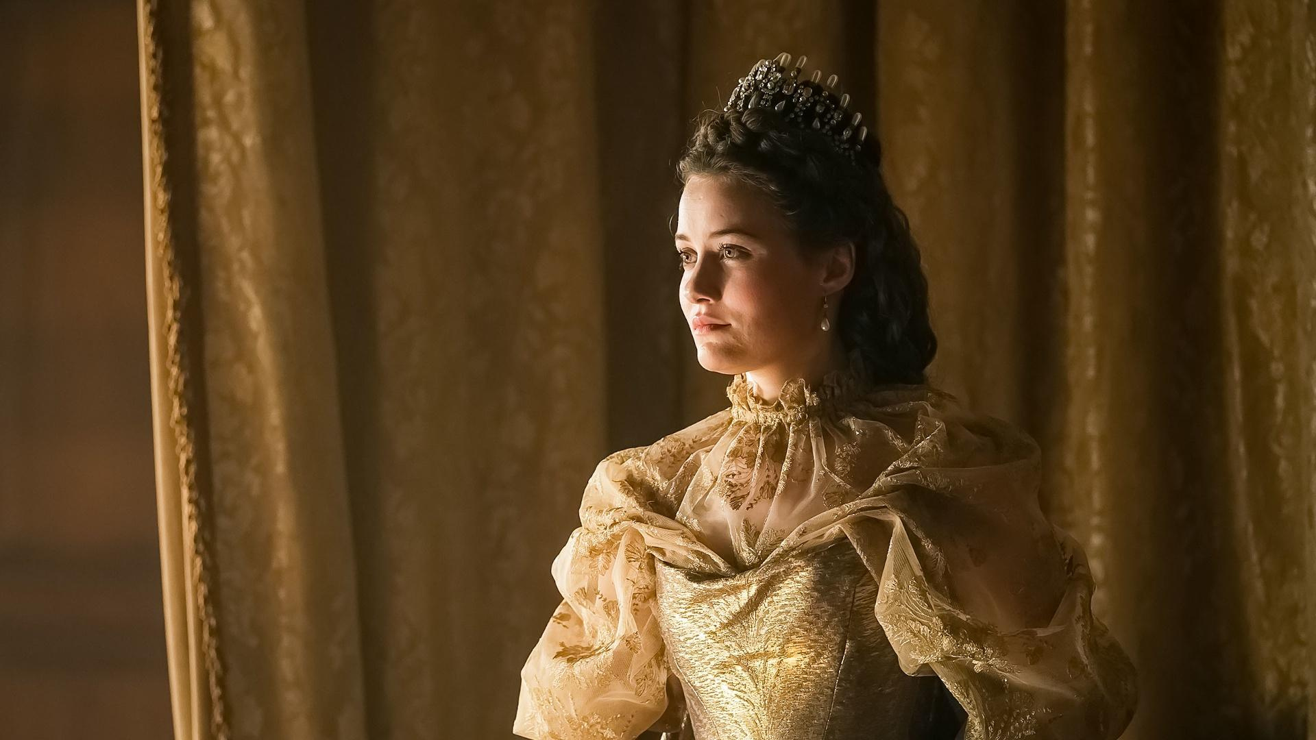 Empress Elisabeth, or Sisi, wearing an ornate gold dress and a jeweled crown, gazing into the distance. 