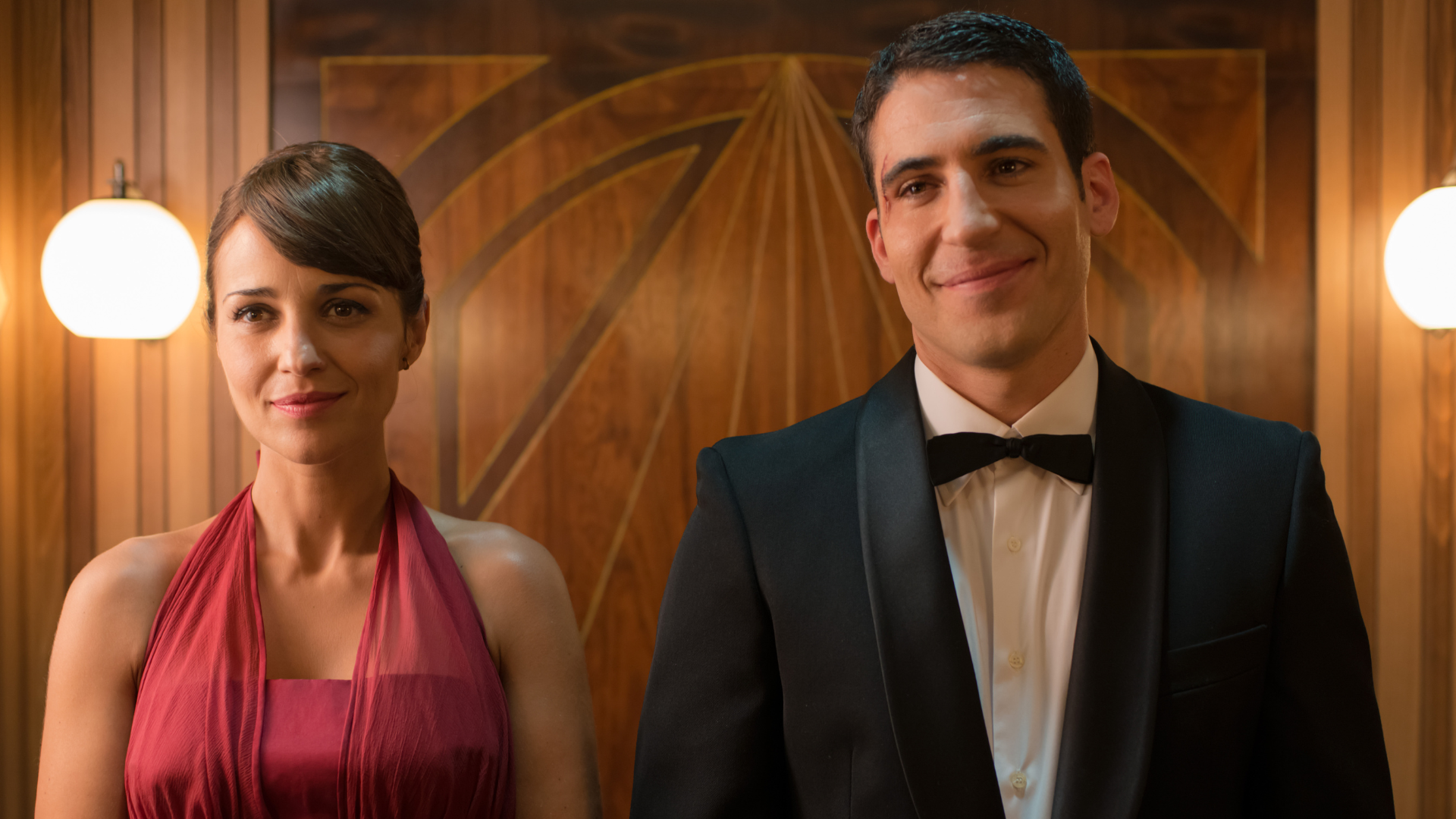 From left, Ana and Alberto standing side by side, both wearing formal outfits with happy expressions. 